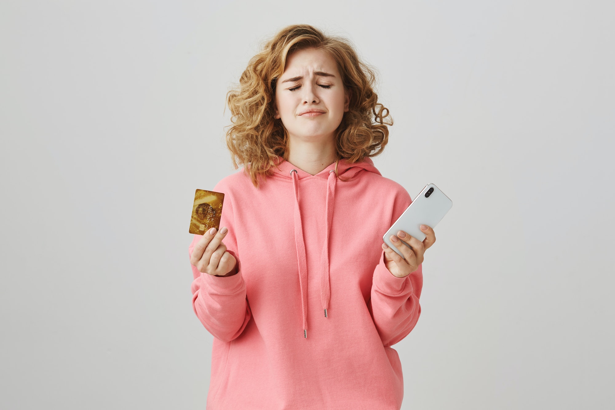 Oh no, I am broke. Portrait of gloomy attractive girl with curly hair holding credit card and